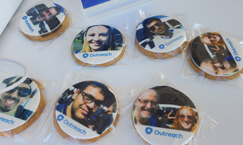 Edible selfie cookies at SaaStr with photos of attendees in top 2/3 of sugar cookie and bottom 1/3 icing with Outreach logo