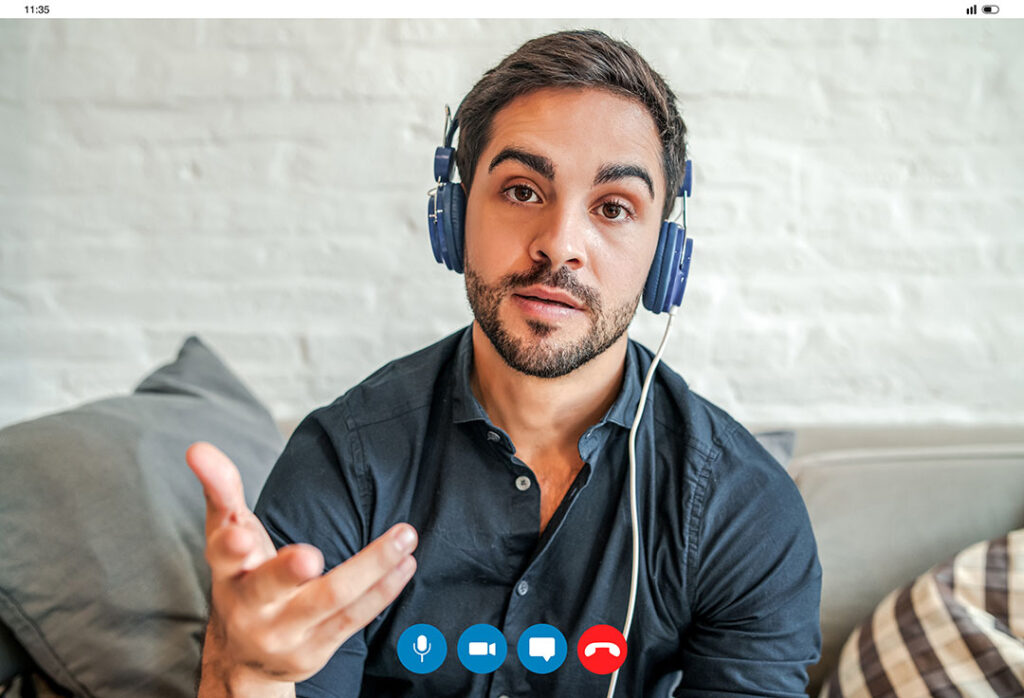 Young professional sitting on a couch with headphones recording a video